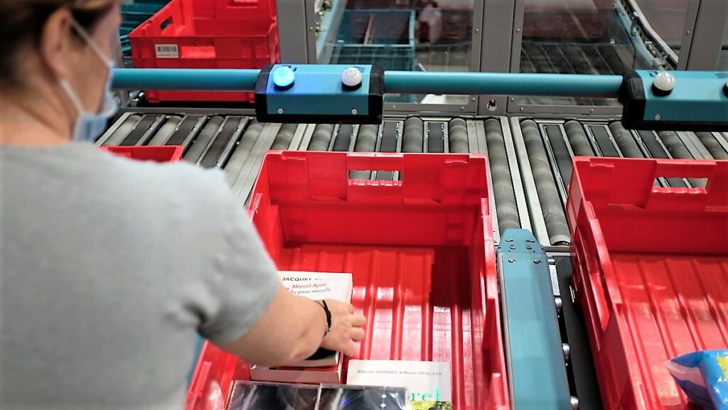 Warehouse worker worker sorting item in a pallet on a conveyor belt